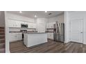 Modern kitchen with white cabinetry, granite countertops, stainless steel appliances, and hardwood floors at 10448 Ladybug Cv, Parrish, FL 34219