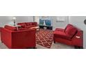 Bright living room with red furniture, rug, and a large television for entertainment at 10448 Ladybug Cv, Parrish, FL 34219