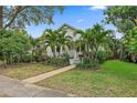 Charming home with mature tropical landscaping, lush green lawn and a welcoming walkway leading to the front porch at 1211 14Th N St, St Petersburg, FL 33705