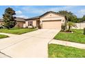 Charming one-story home featuring a well-manicured lawn, neutral tan paint, and a two-car garage at 12428 Chaya Ct, Spring Hill, FL 34610