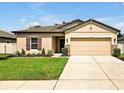Beautiful home featuring a well-manicured lawn, neutral tan paint, and a two-car garage at 12428 Chaya Ct, Spring Hill, FL 34610