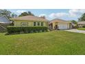 Charming yellow home with a well-manicured lawn and beautiful landscaping at 15005 Roundup Dr, Tampa, FL 33624