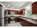 Well-lit kitchen featuring stainless steel appliances, dark wood cabinets, and tile flooring at 1880 Fuller Dr, Clearwater, FL 33755