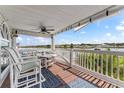 Charming outdoor balcony with beautiful water view, comfortable seating, ceiling fan, and classic blue outdoor rug at 20019 Gulf Blvd # 1, Indian Shores, FL 33785