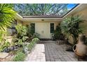 Inviting courtyard with a koi pond, brick pavers, lush plants, and double doors at 2503 Victarra Cir, Lutz, FL 33559