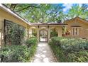 Arched walkway leading to courtyard with lush, manicured bushes and black metal gate at 2503 Victarra Cir, Lutz, FL 33559