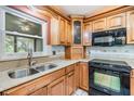 Kitchen featuring wooden cabinetry, tile backsplash, black appliances, and a stainless steel sink at 2911 Pemberton Creek Dr, Seffner, FL 33584