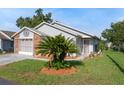 Charming single-story home featuring a well-manicured lawn and tropical landscaping, creating a welcoming curb appeal at 37420 Teaberry Loop, Zephyrhills, FL 33542
