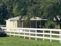 Outbuilding with screened-in porch that sits beyond a white fence at 4316 E Knights Griffin Rd, Plant City, FL 33565