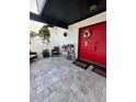 Covered front porch with seating area, decorative plants, and a bright red front door at 7312 Nova Cir, Tampa, FL 33634