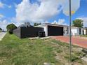 View of a single-story home with black garage door and vinyl fence in a well-manicured landscape at 7834 Treasure Pointe Dr, Port Richey, FL 34668