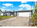 Single-story home with a two-car garage and well-maintained landscaping situated under a bright blue sky with clouds at 13926 Darlene Ave, Hudson, FL 34667