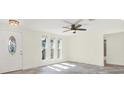 Bright living room featuring a decorative front door, multiple windows, and tile flooring under a modern ceiling fan at 13926 Darlene Ave, Hudson, FL 34667