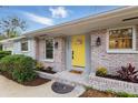 Inviting front entrance showcasing a vibrant yellow door, brick accents, and manicured landscaping at 1470 Serpentine S Dr, St Petersburg, FL 33705