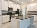 Modern kitchen featuring white cabinets, stainless steel appliances, and a granite island at 24815 Lambrusco Loop, Lutz, FL 33559