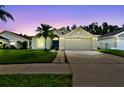 Charming home exterior at dusk with a two-car garage, green lawn, and landscaped front yard at 30918 Burleigh Dr, Wesley Chapel, FL 33543