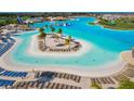 Aerial view of community pool featuring a sandy beach, cabanas, and lounge chairs for relaxing at 30936 Summer Sun Loop, Wesley Chapel, FL 33545
