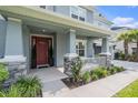 Inviting front porch with decorative columns and stone accents, leading to a red front door, enhancing curb appeal at 33774 Castaway Loop, Wesley Chapel, FL 33543