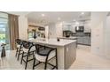 Modern kitchen island with seating, light gray cabinets, stainless steel appliances, and view of the backyard at 33774 Castaway Loop, Wesley Chapel, FL 33543