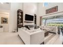 Bright living room featuring soaring ceilings, a modern fireplace, built-in shelves, and sliding glass doors to outdoor patio at 33774 Castaway Loop, Wesley Chapel, FL 33543
