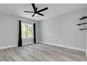 Neutral bedroom featuring wood-look floors, a ceiling fan, a large window, and modern shelving accents at 3595 41St S Ln # L, St Petersburg, FL 33711
