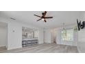 Bright, open-concept living room with wood-look floors, white walls, ceiling fan and kitchen bar seating at 3595 41St S Ln # L, St Petersburg, FL 33711