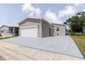A charming home featuring tan siding, a garage, and a red front door with a freshly painted driveway at 8471 Fantasia Park Way, Riverview, FL 33578