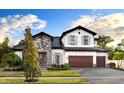 Charming two-story home featuring mixed stone and stucco, a three-car garage, and beautifully landscaped front yard at 125 Hidden Estates Ct, Brandon, FL 33511