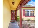 A covered front porch welcomes you to this home, enhanced with a red front door and decorative light fixture at 14339 Mayer Ave, Hudson, FL 34669