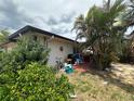 Backyard showing exterior of home, with room for seating, a bicycle, and surrounded by lush tropical plants at 1559 San Roy Dr, Dunedin, FL 34698