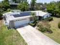 Inviting single-story home featuring a two-car garage, solar panels, and lush front lawn with tasteful landscaping at 1598 Brookside Blvd, Largo, FL 33770