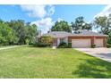 Charming brick home featuring a two-car garage, manicured lawn, and mature landscaping at 1815 Durant Rd, Valrico, FL 33596