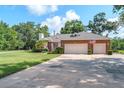 Charming brick home featuring a two-car garage, manicured lawn, and mature landscaping at 1815 Durant Rd, Valrico, FL 33596