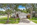 Traditional home with a well-manicured lawn, mature trees, and a two-car garage at 2601 Brookville Dr, Valrico, FL 33596