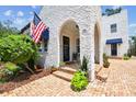 Charming stucco home featuring arched entryway, brick steps, and an American flag at 3405 W Palmira Ave, Tampa, FL 33629
