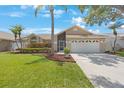 Beautifully landscaped front yard with green grass, tropical palms, and a two-car garage at 3834 102Nd N Pl, Clearwater, FL 33762