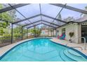 Screened pool with blue tiles, string lights, and patio seating area at 3968 Orchard Hill Cir, Palm Harbor, FL 34684