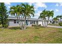 Inviting single-story home with a lush front lawn, palm trees, and a convenient two-car garage at 4210 Palm Dr, Punta Gorda, FL 33950