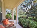 Covered front porch featuring comfortable wicker seating and views of the landscaped yard at 5401 Match Point Pl, Lithia, FL 33547