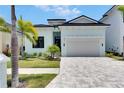 Beautiful light blue, two-story home featuring a two-car garage, manicured lawn, and palm trees at 6534 Simone Shores Cir, Apollo Beach, FL 33572
