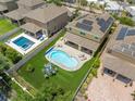 Aerial view of a backyard with a pool, a patio, an artificial turf area, and solar panels on the roof at 10596 Lake Seminole Ter, Seminole, FL 33772