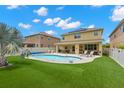 Backyard oasis with a pool, patio area with lounge chairs, and well-maintained artificial grass at 10596 Lake Seminole Ter, Seminole, FL 33772