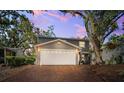 Inviting two-story home featuring a brick driveway, attached garage, manicured landscaping, and mature trees at dusk at 1120 43Rd N Ave, St Petersburg, FL 33703