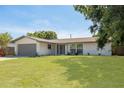 Beautiful single-story home with a well-manicured lawn, grey trim and a two-car garage on a sunny day at 11296 115Th St, Largo, FL 33778