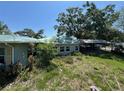 The side and back exterior shows an attached carport with an overgrown yard and weathered siding at 2402 E 148Th Ave, Lutz, FL 33549