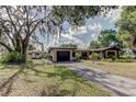 View of the exterior of the home with a driveway, showcasing lush landscaping and mature trees at 34389 Orchid Pkwy, Ridge Manor, FL 33523