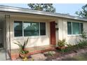 Close-up of a home entrance with a red door, tiled porch, and decorative plants at 406 2Nd Sw St, Ruskin, FL 33570
