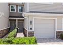 Close up of a townhome exterior with a one-car garage, brick paved drive and tropical shrubs at 5496 Riverwalk Preserve Dr, New Port Richey, FL 34653