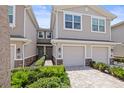 Townhomes with garage, double doors, brick paved drive, tropical shrubs, and street lamp at 5496 Riverwalk Preserve Dr, New Port Richey, FL 34653