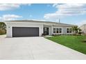 Beautifully renovated home features a lush front yard, modern front door, and gray garage door at 718 Desert Hills Way, Sun City Center, FL 33573